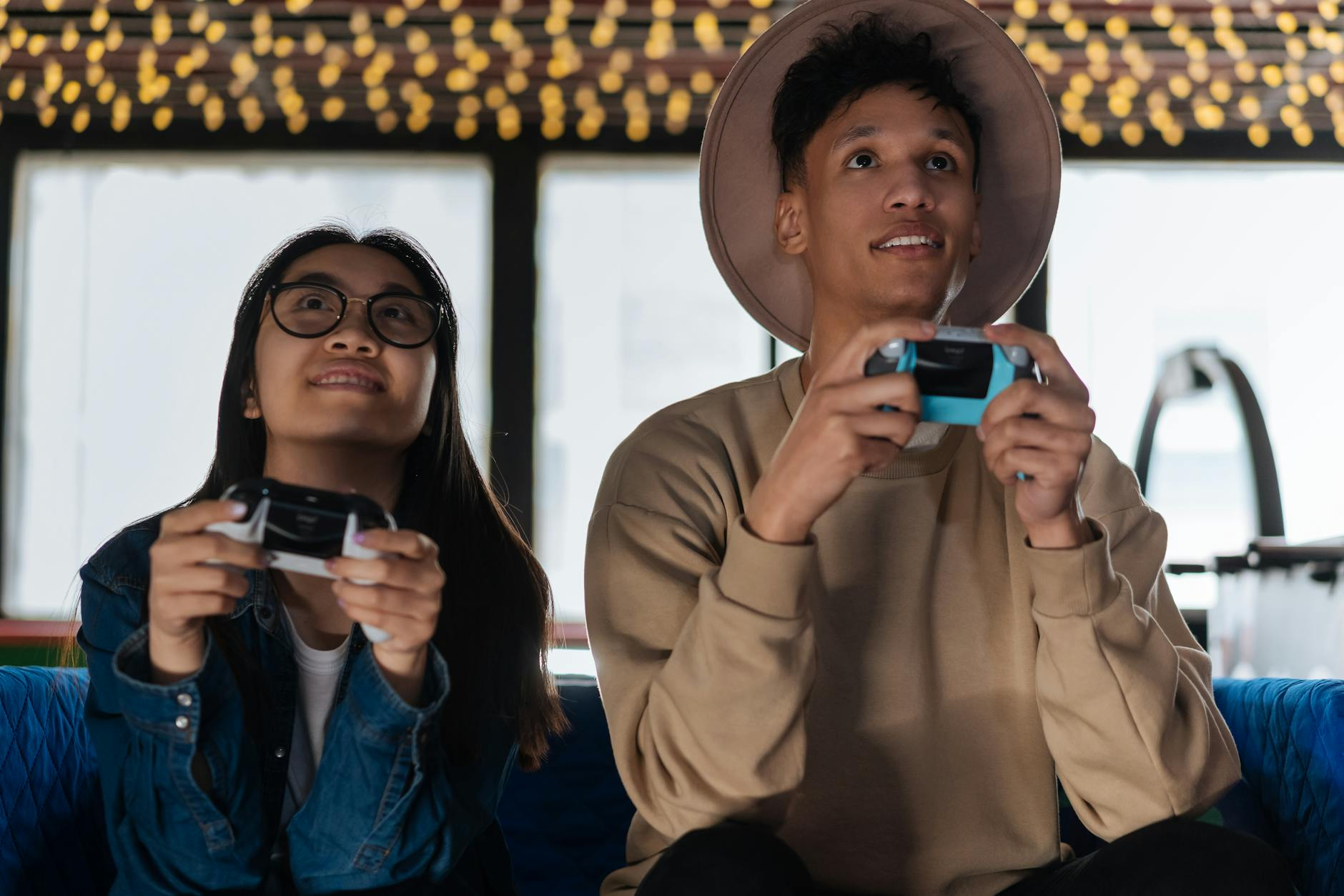 man and woman holding game controllers and playing